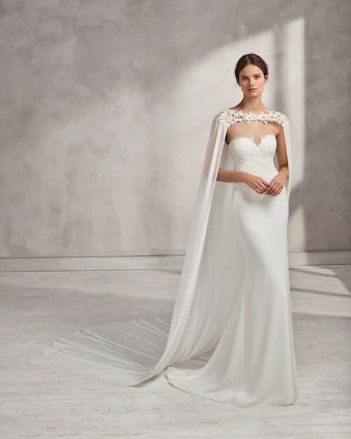 Mermaid-style crepe Georgette and guipure lace wedding dress with sweetheart neckline and cape.