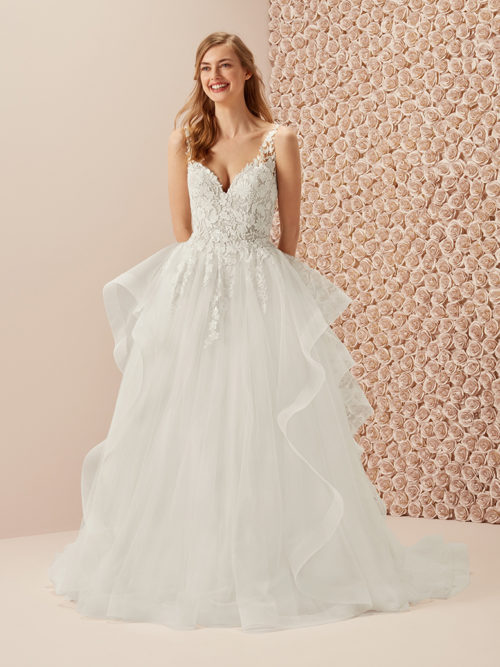 Feminine and very stylish. A princess dress that breaks with the conventions by using the fullness of the uneven ruffles in the tulle skirt combined with a sensual lace bodice with embroidered flowers and v-neck and v-back.