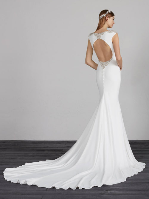 Discretion is the key to elegance. A dramatic and very sophisticated dress that uses crepe as the fabric for outlining a stunning mermaid silhouette. The low waist of the skirt and the bateau neckline slim the figure, while the open back adorned with beaded sparkles gives it a touch of seductiveness and romanticism at the same time.