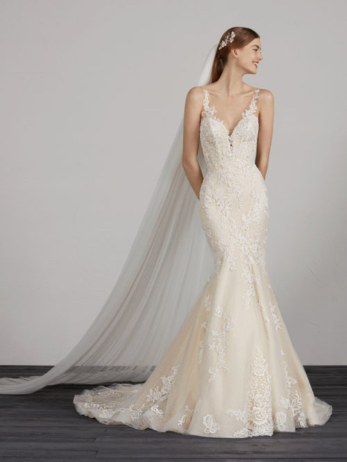 We break away from white to create a romantic, sexy and very elegant design. A tulle and lace mermaid dress with hundreds of floral details that envelop the bodice and skirt with low waist. The v-neck and v-back accentuate the illusion contours in crystal tulle and lace that make the edges of the dress fade into a very stylish second-skin look