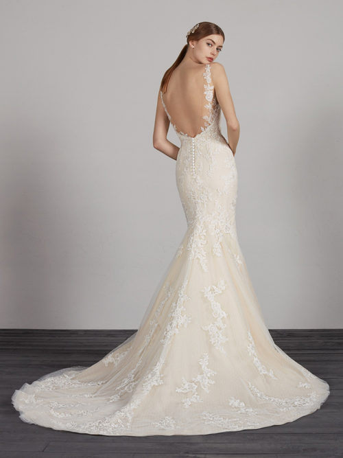 We break away from white to create a romantic, sexy and very elegant design. A tulle and lace mermaid dress with hundreds of floral details that envelop the bodice and skirt with low waist. The v-neck and v-back accentuate the illusion contours in crystal tulle and lace that make the edges of the dress fade into a very stylish second-skin look