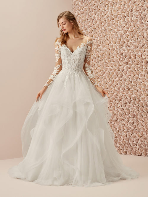 Simple, elegant and with a very personal touch. A princess dress that puts the spotlight on the low-waist skirt crafted of uneven tulle ruffles in cascade, and combines it with a sensual embroidered bodice with a v-neck and an illusion tulle tattoo back. The long sleeves, also with a second-skin look, are adorned with a row of buttons on the cuffs.