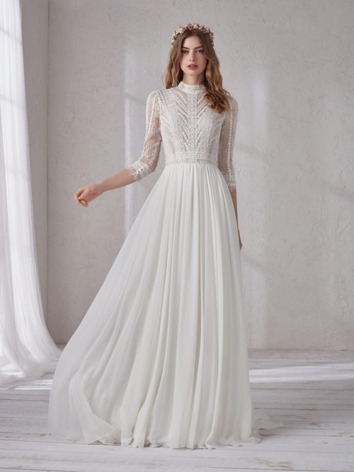 Bohemian with a chic touch and the delicateness of the most exquisite romanticism. That describes this sensual dress with chiffon evasé skirt with natural waist, combined with an original Chantilly and semi-sheer guipure bodice with high neckline and 3/4 sleeves.