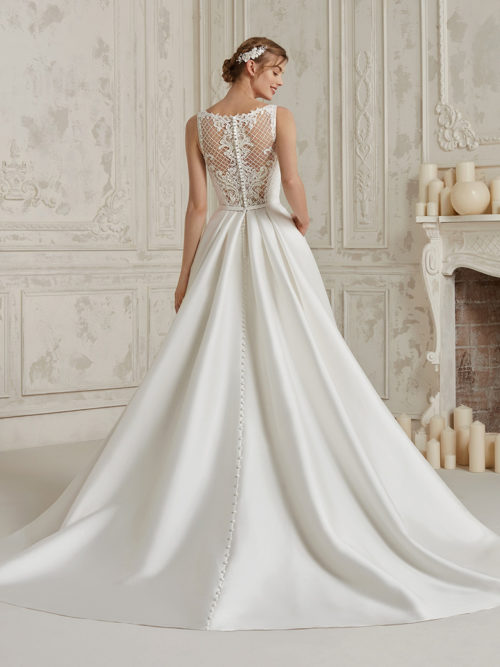 Elegant, sensual and stylish. A spectacular mixture that successfully blends a sensational mikado princess skirt with a natural waist and pockets, and a sensational tulle and beaded bodice outlined by a sleeveless bateau neckline.